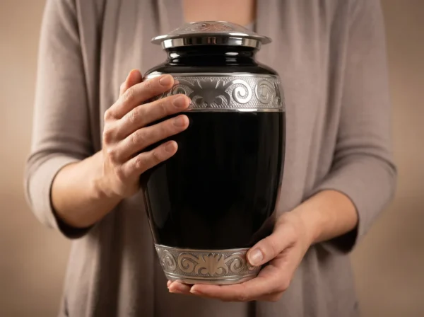 Person holding the full-size black enamel adult cremation urn to show its scale