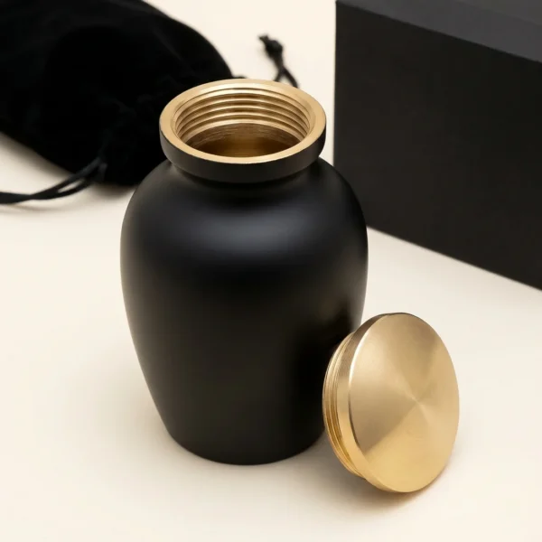 Black and gold keepsake urn with the threaded lid removed