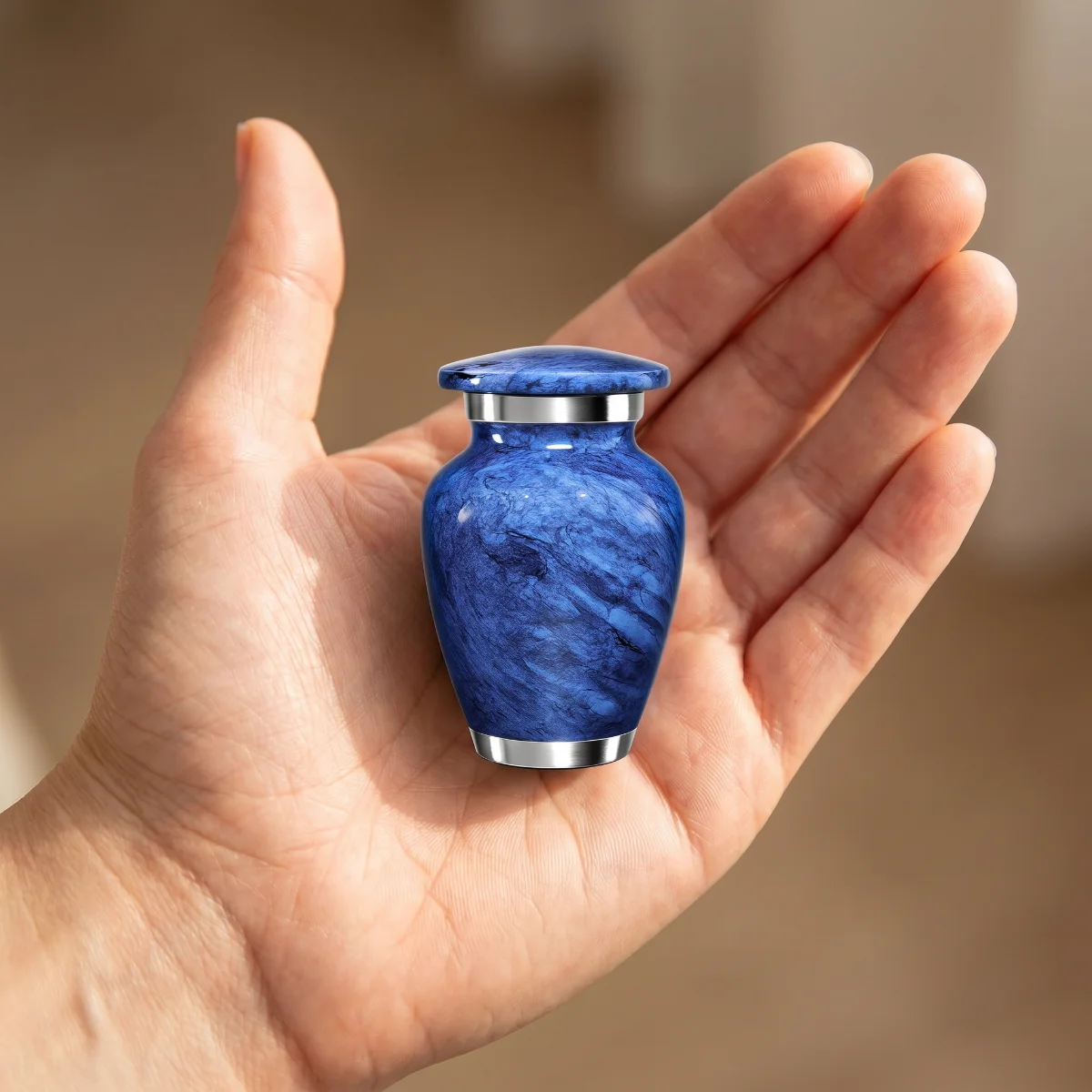 Small blue marble keepsake urn in an open palm to show its size