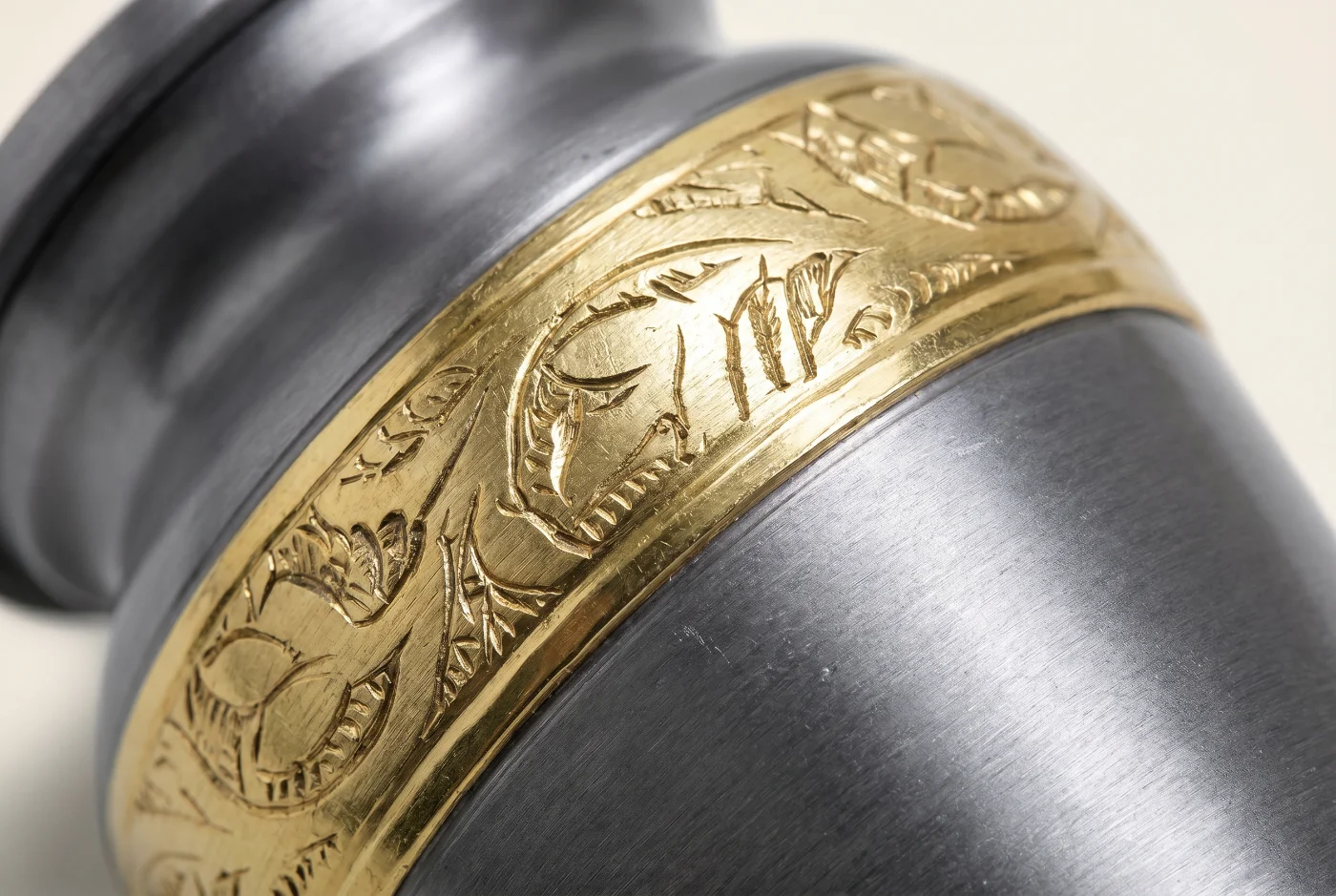 Close-up of the brushed pewter-grey finish and gold engraved band