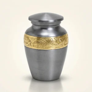 Pewter-grey small keepsake urn with an ornate gold engraved band, studio shot