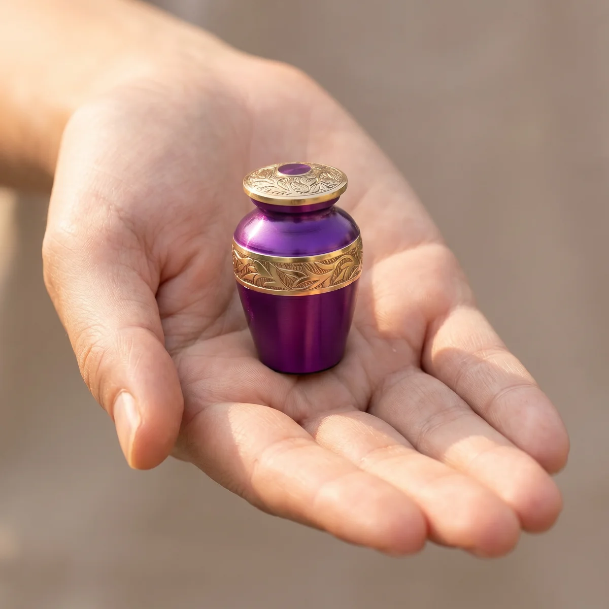 Small purple keepsake urn resting in an open palm to show its size