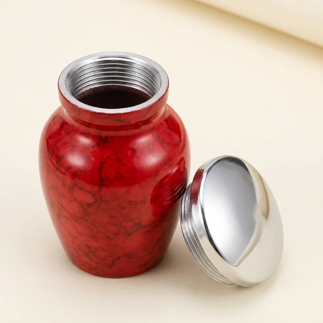 Red keepsake urn with the silver threaded lid removed