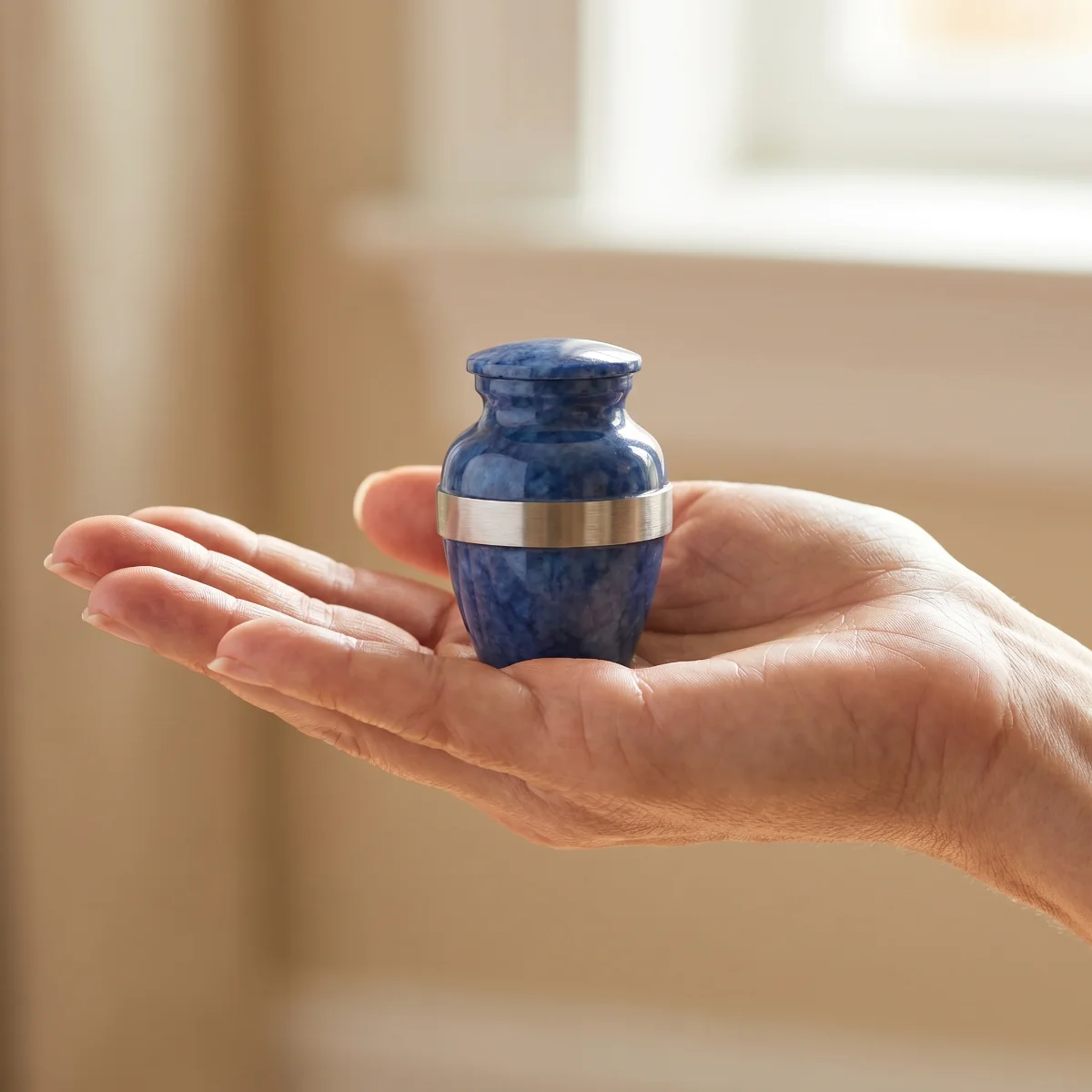 Single blue keepsake urn in an open palm to show its size