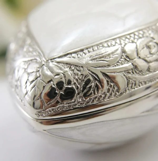 Close-up of the engraved silver florals and pearl enamel on the heart keepsake