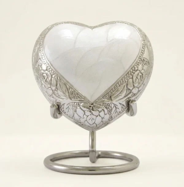 White enamel heart keepsake urn with silver floral engraving on its display stand