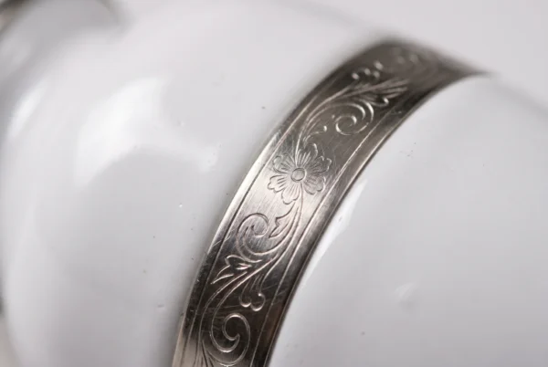 Close-up of the glossy white enamel and ornate silver engraved band