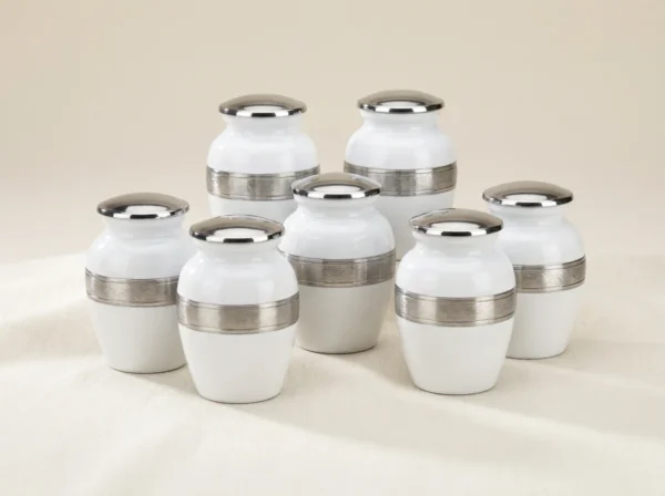 Set of six white enamel keepsake urns with ornate silver bands, studio group shot